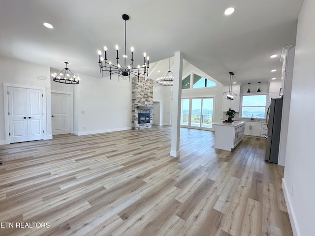 unfurnished dining area with baseboards, a stone fireplace, light wood-type flooring, and recessed lighting