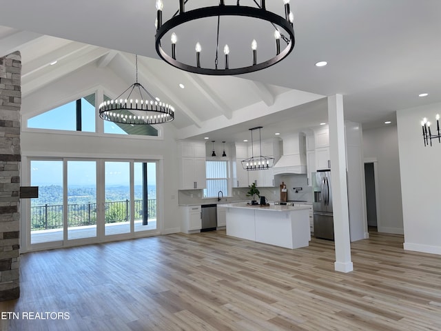 kitchen with a notable chandelier, stainless steel appliances, open floor plan, light countertops, and custom range hood