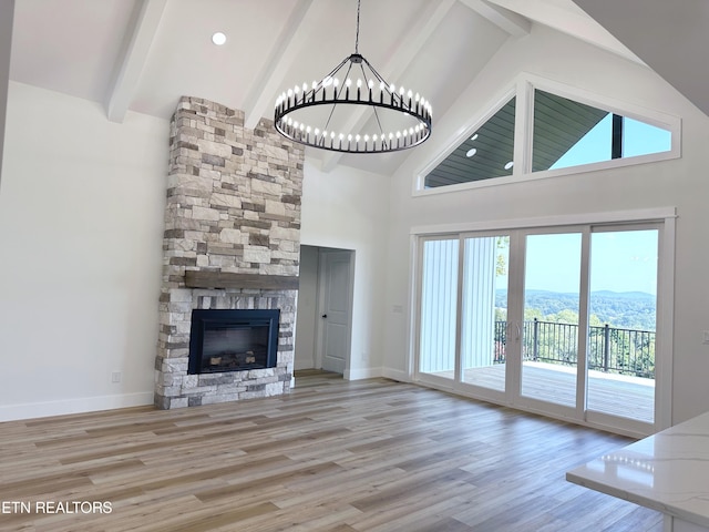 unfurnished living room featuring light wood-style floors, a fireplace, baseboards, and beamed ceiling