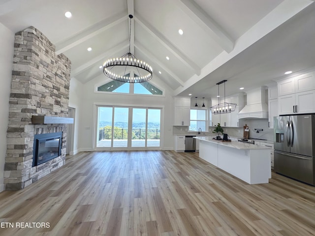 kitchen featuring stainless steel appliances, custom range hood, an inviting chandelier, white cabinets, and high vaulted ceiling