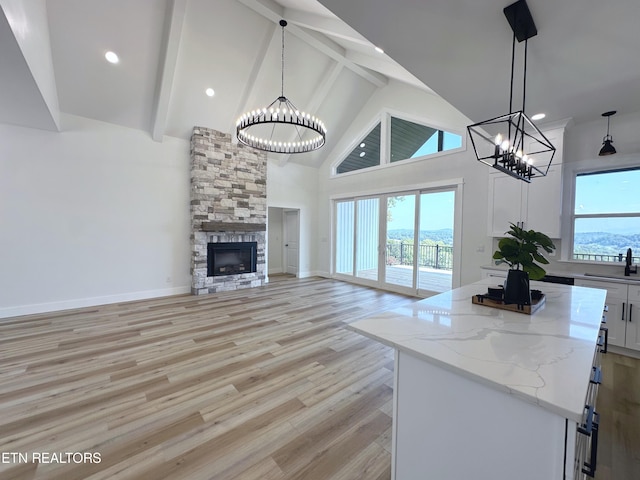 unfurnished living room with a chandelier, high vaulted ceiling, light wood finished floors, and a wealth of natural light