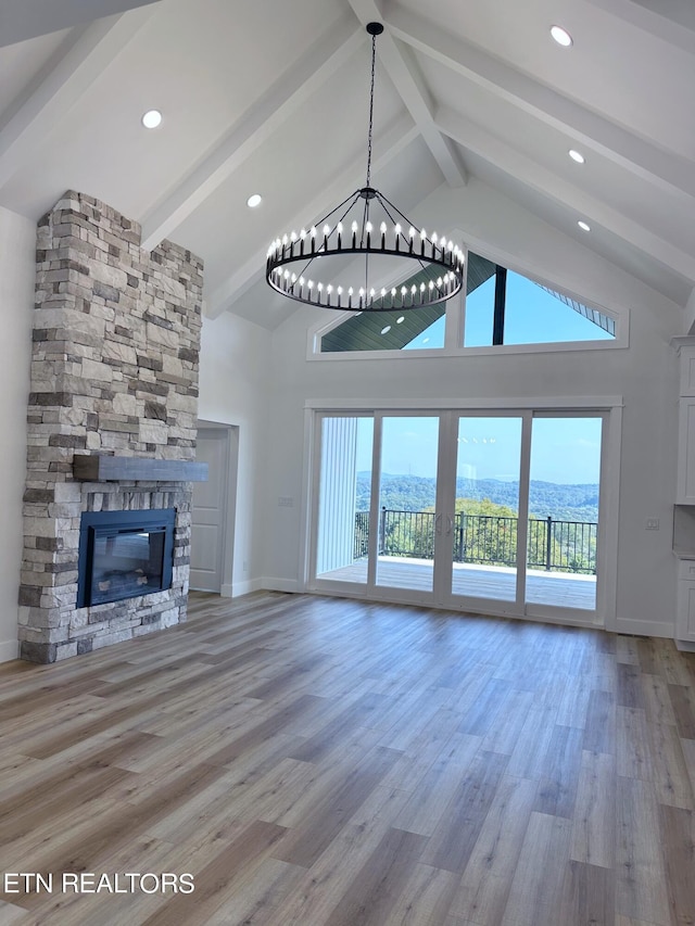 unfurnished living room featuring high vaulted ceiling, a fireplace, beamed ceiling, and wood finished floors