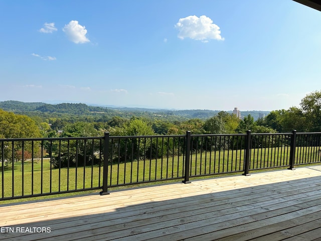 deck featuring a forest view and a lawn