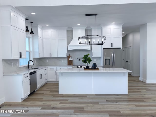 kitchen with appliances with stainless steel finishes, a center island, premium range hood, white cabinetry, and backsplash