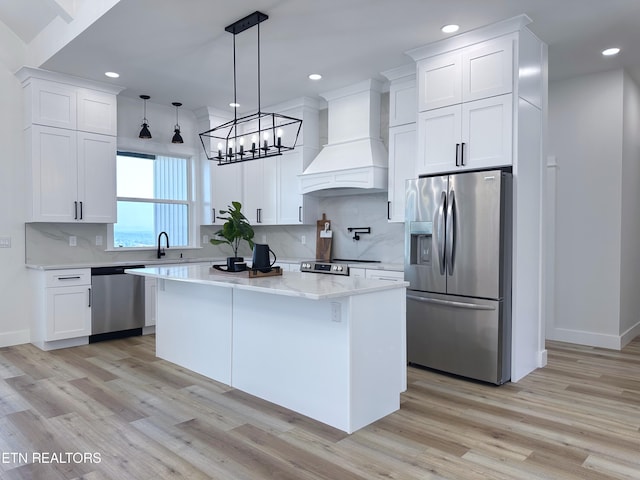 kitchen featuring premium range hood, light wood-style floors, appliances with stainless steel finishes, and white cabinetry