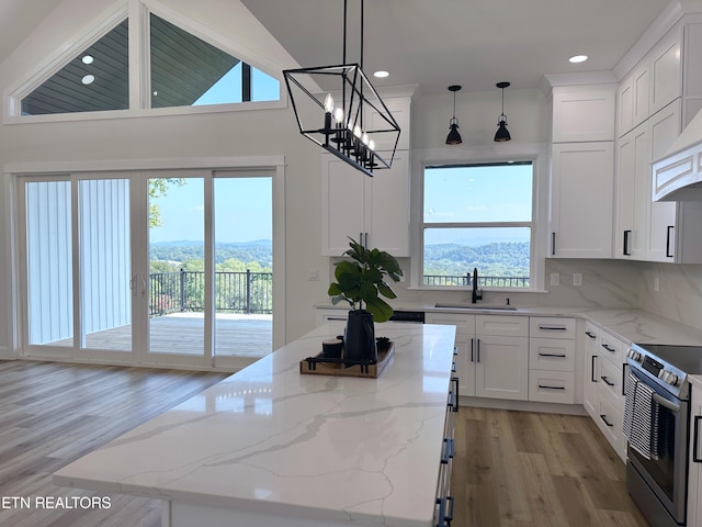 kitchen with light stone counters, stainless steel electric range oven, a sink, and a kitchen island