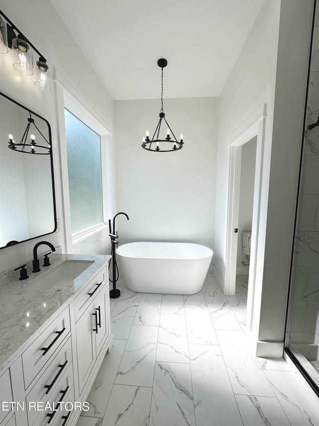 bathroom with toilet, a soaking tub, marble finish floor, vanity, and a chandelier