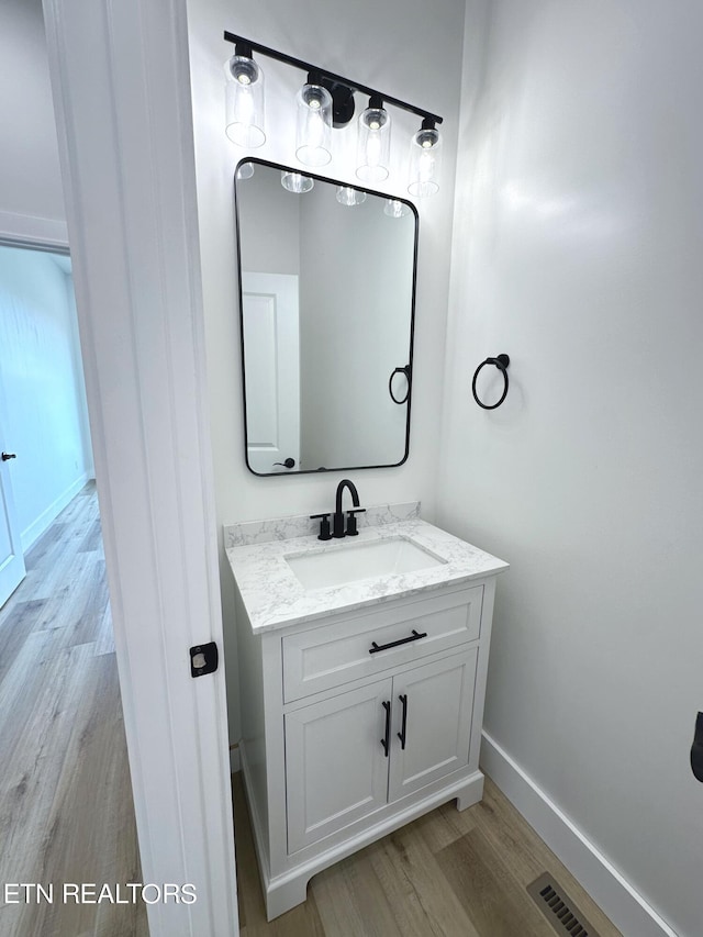 bathroom featuring visible vents, vanity, baseboards, and wood finished floors