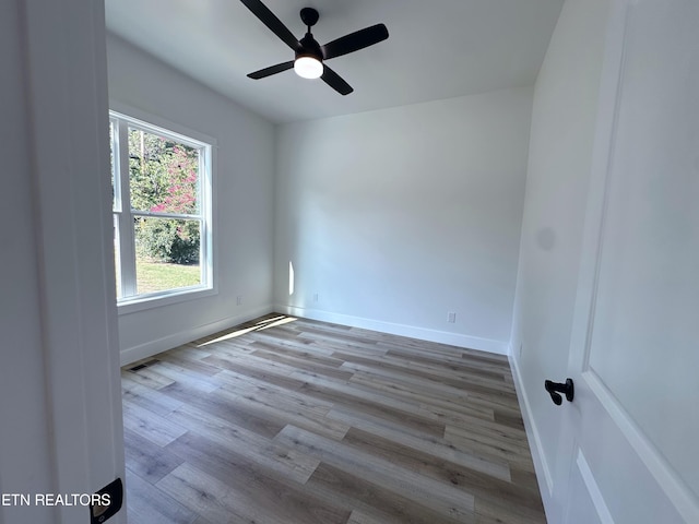 empty room featuring ceiling fan, wood finished floors, visible vents, and baseboards