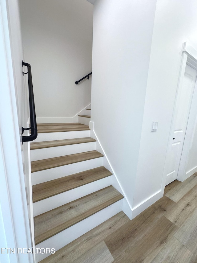 staircase with baseboards and wood finished floors