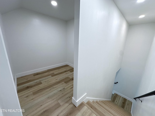 stairway featuring baseboards, wood finished floors, and recessed lighting