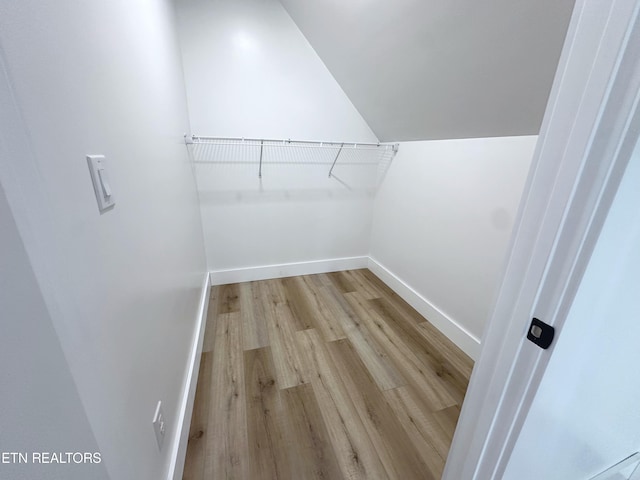 walk in closet with vaulted ceiling and light wood finished floors