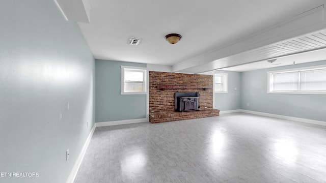 unfurnished living room featuring a brick fireplace and a wood stove