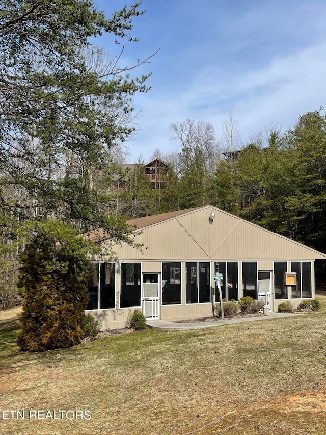 rear view of property with a yard and a sunroom