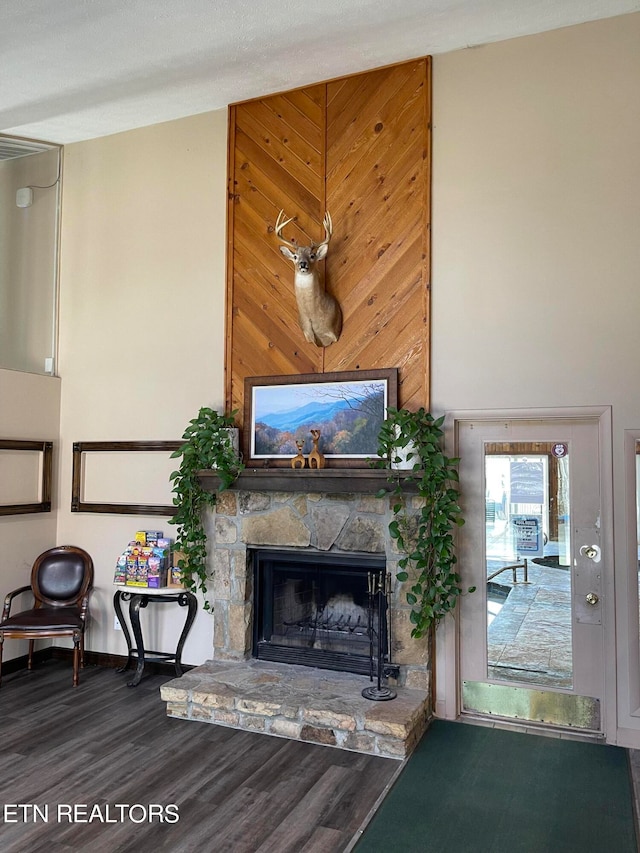 unfurnished living room with wooden walls, dark hardwood / wood-style floors, and a stone fireplace