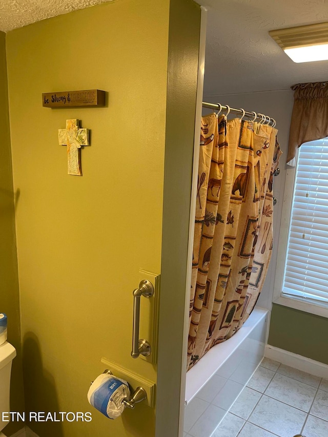 bathroom featuring tile patterned flooring, shower / tub combo with curtain, and a textured ceiling