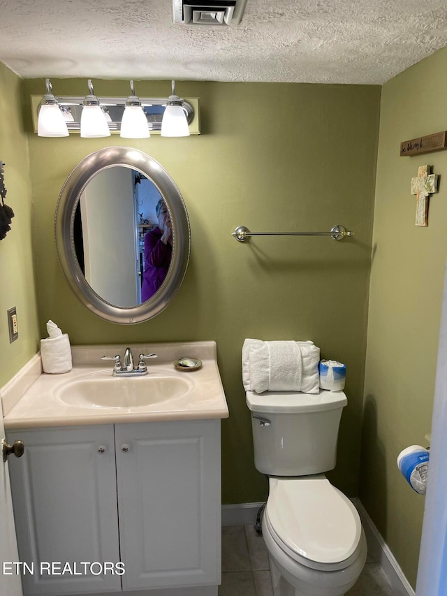 bathroom with vanity, toilet, tile patterned floors, and a textured ceiling