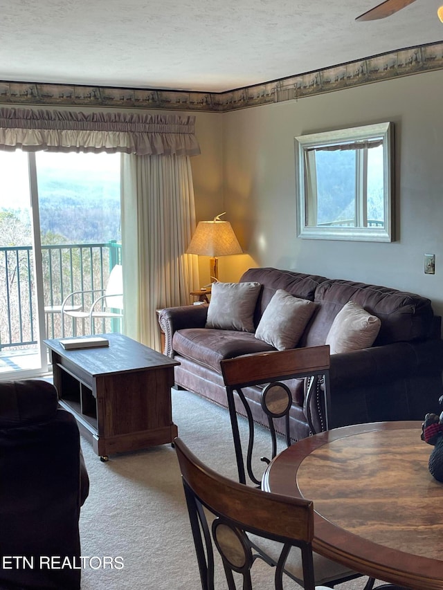 living room featuring ceiling fan, a textured ceiling, and carpet floors