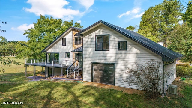 back of property featuring central AC unit, a garage, a yard, and a deck