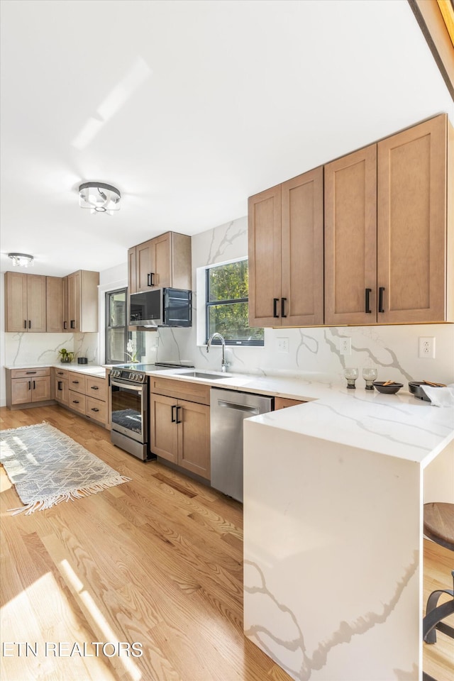 kitchen featuring sink, light hardwood / wood-style flooring, a breakfast bar area, stainless steel appliances, and kitchen peninsula