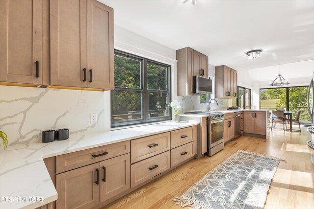 kitchen with stainless steel appliances, plenty of natural light, light hardwood / wood-style floors, and decorative backsplash