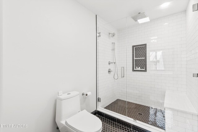 bathroom with a shower with door and toilet