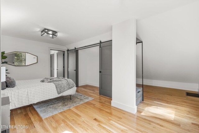 bedroom featuring wood-type flooring and a barn door