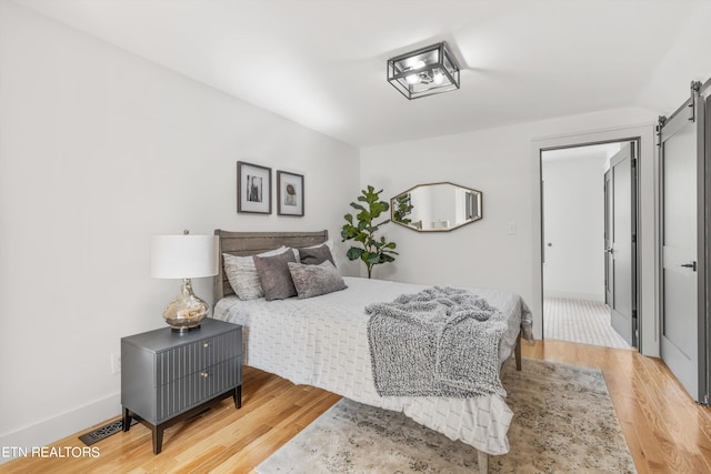 bedroom featuring light hardwood / wood-style floors and a barn door