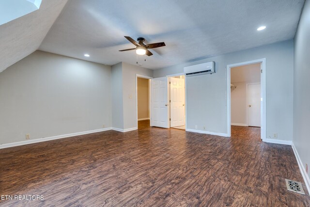 unfurnished bedroom featuring dark wood-type flooring, ceiling fan, an AC wall unit, and vaulted ceiling