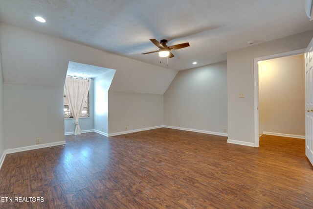 bonus room with a textured ceiling, lofted ceiling, ceiling fan, and dark hardwood / wood-style floors