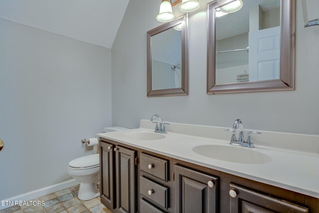 bathroom with vanity, toilet, tile patterned floors, and lofted ceiling