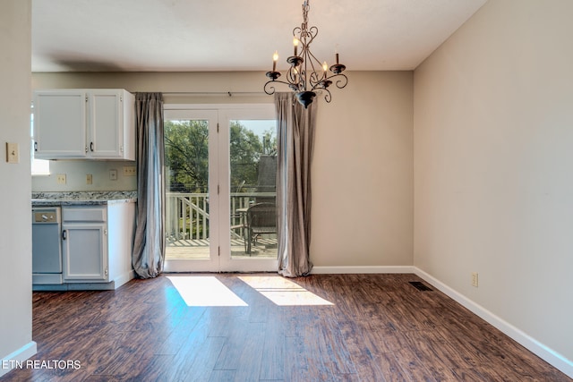 unfurnished dining area featuring dark wood-type flooring and a notable chandelier