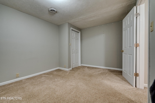 unfurnished bedroom featuring a textured ceiling, a closet, and light carpet