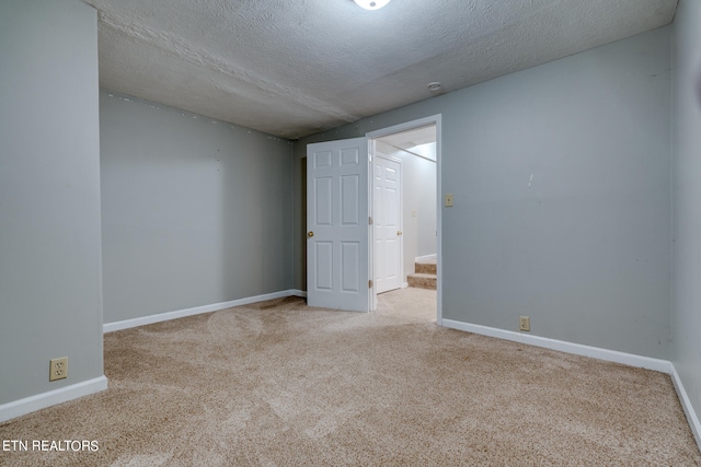 empty room with light carpet and a textured ceiling