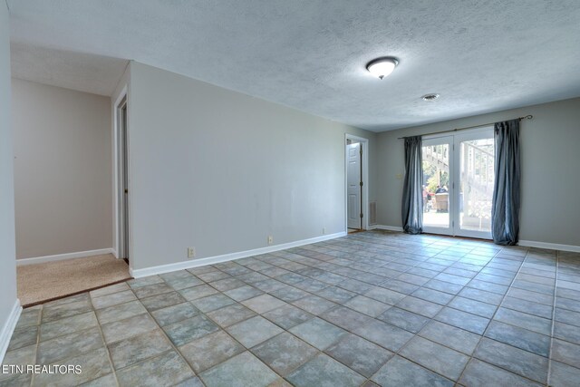 unfurnished room featuring light tile patterned floors and a textured ceiling