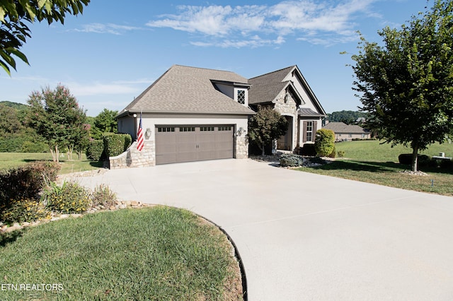 275 Hummingbird Dr, Vonore, TN 37885 - view of front facade with a shingled roof, a front lawn, driveway, stone siding, and an attached garage