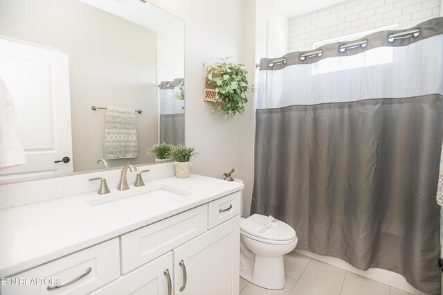 bathroom featuring tile patterned floors, a shower with curtain, toilet, and vanity