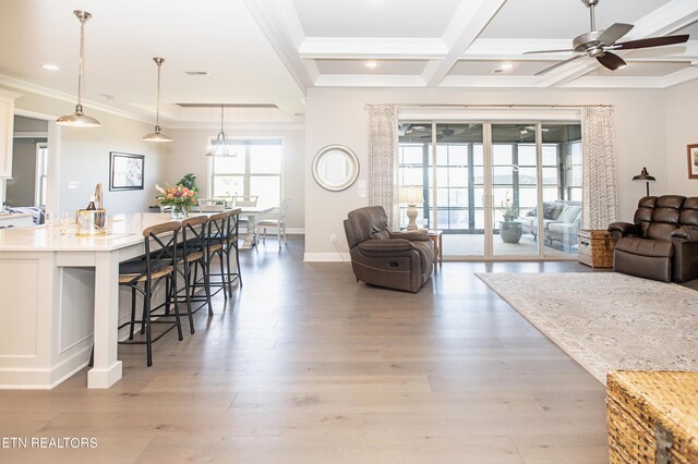 living room with ornamental molding, coffered ceiling, light hardwood / wood-style flooring, and ceiling fan