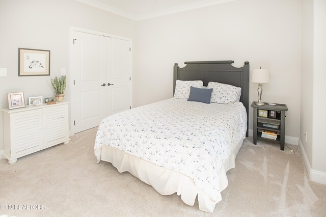 bedroom featuring a closet, light carpet, and ornamental molding