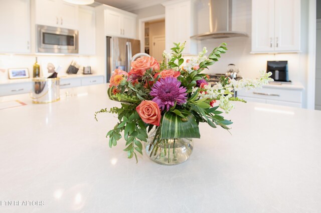 kitchen featuring stainless steel appliances, wall chimney exhaust hood, and white cabinetry