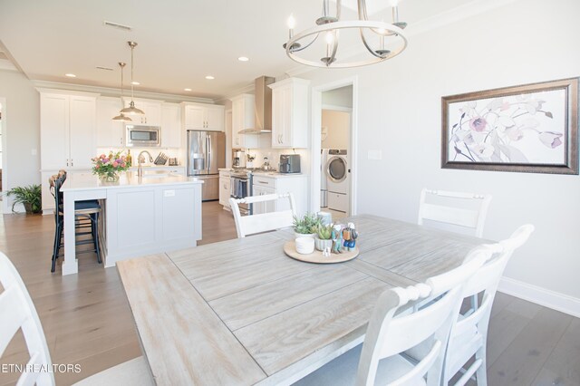 dining space with washer / dryer, a chandelier, hardwood / wood-style flooring, and sink