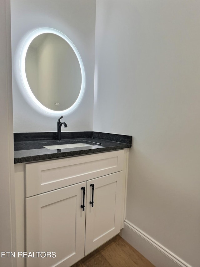 bathroom featuring vanity, baseboards, and wood finished floors