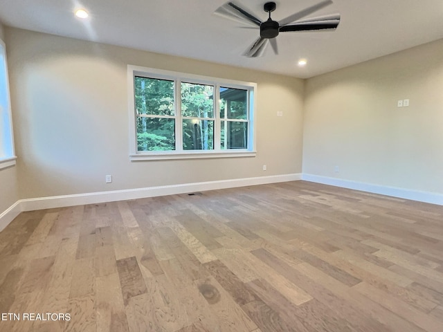 spare room with baseboards, ceiling fan, and light wood-style flooring
