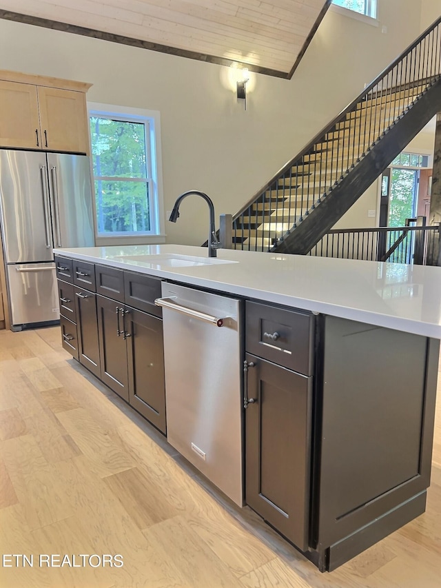 kitchen featuring an island with sink, light hardwood / wood-style flooring, sink, and appliances with stainless steel finishes