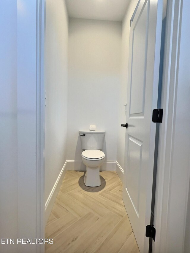 bathroom featuring parquet floors and toilet