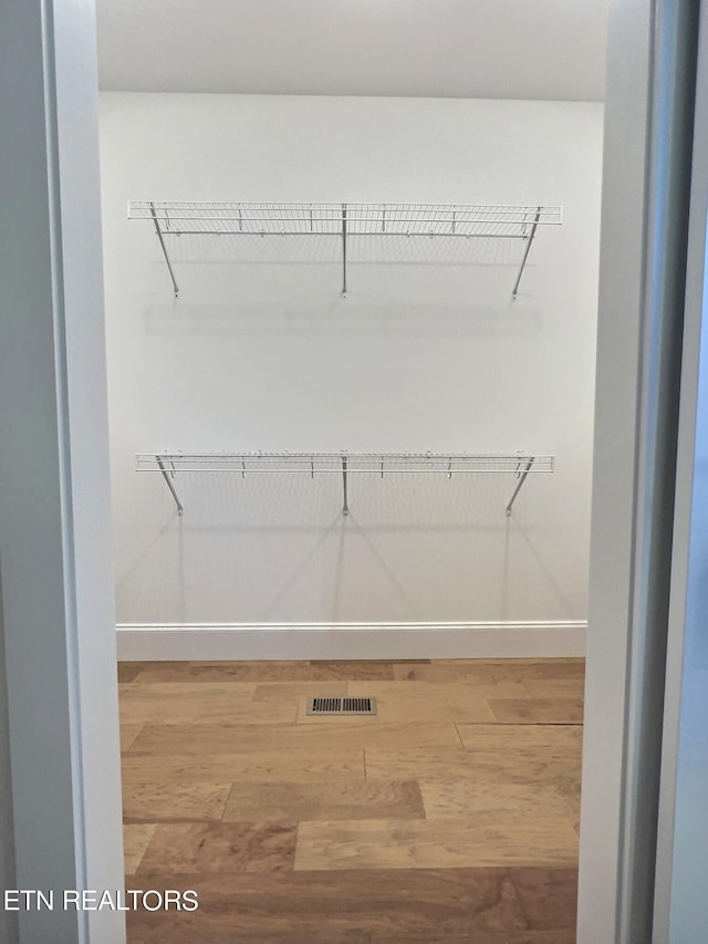 walk in closet with visible vents and wood finished floors