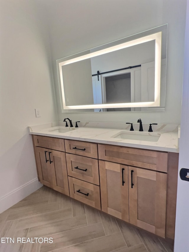 bathroom featuring double vanity, baseboards, and a sink