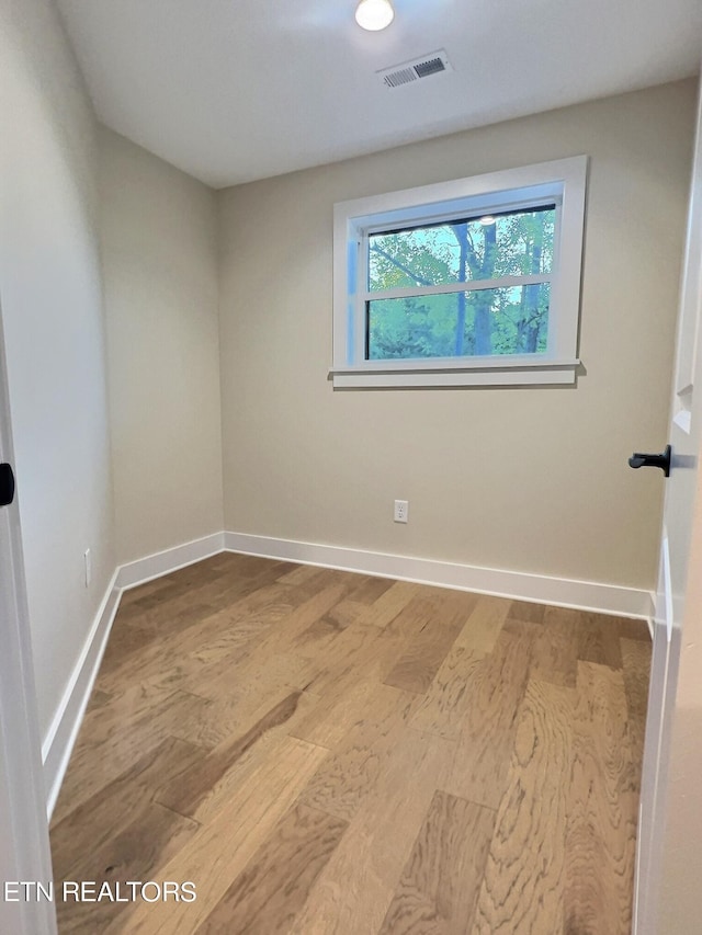 unfurnished room with baseboards, visible vents, and wood finished floors