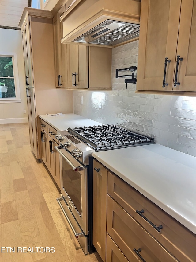 kitchen with high end stove, tasteful backsplash, custom exhaust hood, and light countertops