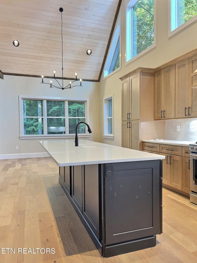 kitchen with a wealth of natural light, a chandelier, a kitchen island with sink, and light hardwood / wood-style flooring